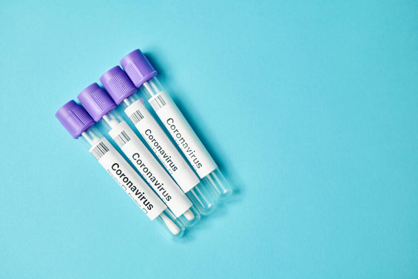 Medical tubes with swab samples for analysis of coronavirus on blue background. - 写真・画像