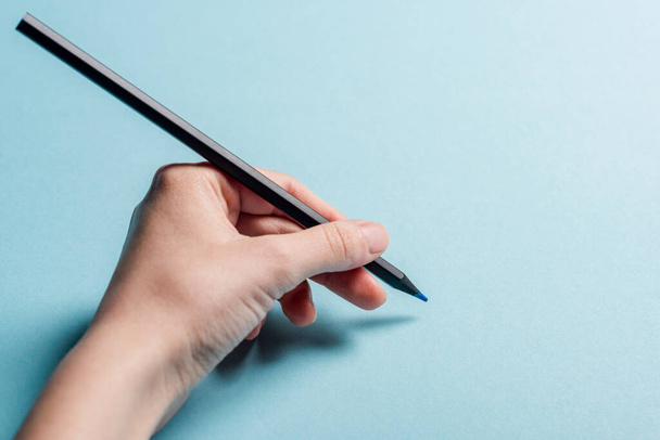 Cropped view of man holding pencil on blue background - Foto, immagini