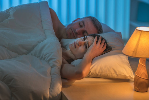 落ち込んでいる女性はベッドの上に男と横になっている。夜の時間 - 写真・画像