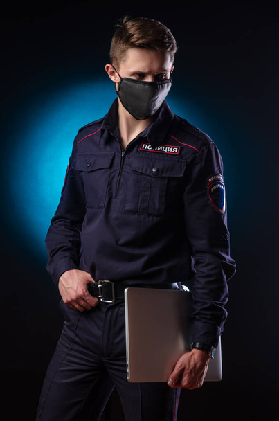 Komea mies poliisiasussa läppäri kasvoillaan ja lääketieteellinen naamio. Englanti käännös Poliisi  - Valokuva, kuva