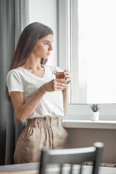 Beautiful woman drinking morning tea behind window. Challenge of a new day. Copy space - Φωτογραφία, εικόνα