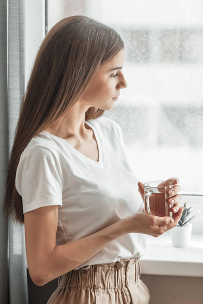 Beautiful woman drinking morning tea behind window. Challenge of a new day. Copy space - Foto, Imagen