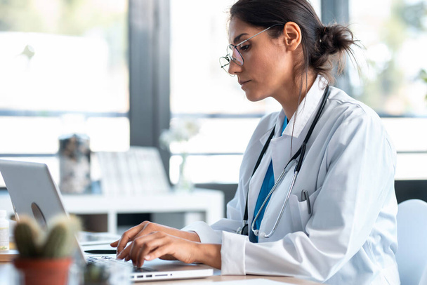 Prise de vue d'une femme médecin sérieuse travaillant avec son ordinateur portable lors de la consultation
. - Photo, image