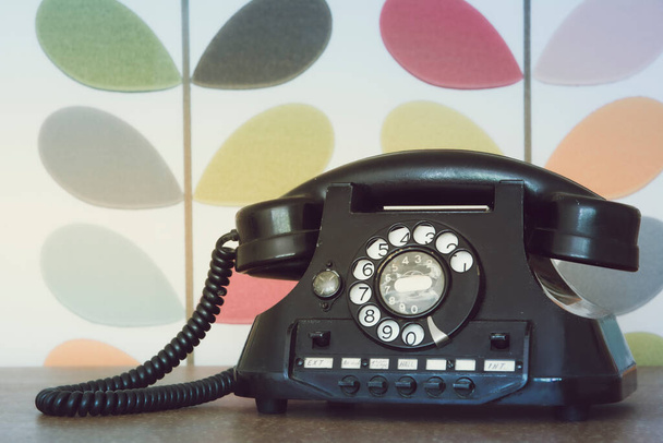Old retro and vintage phone against colorful wallpaper. Muted processing - Photo, Image
