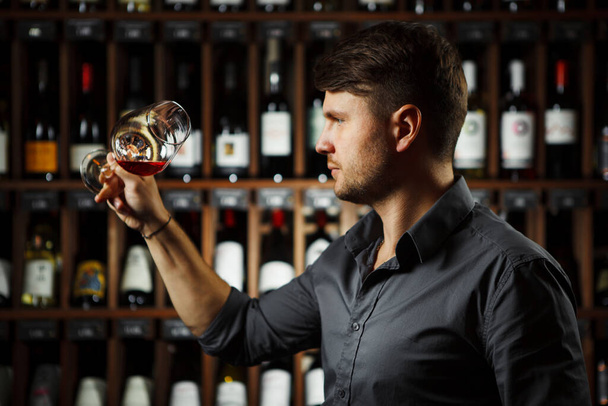 Bokal of red wine on background, male sommelier appreciating drink - Foto, Imagen