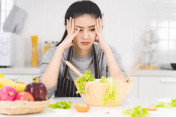 Young woman or housewife is bored of cooking, which consists of a variety of fruits and vegetables for the family. - Photo, Image