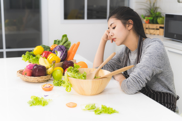 Молодая женщина или домохозяйка скучает от приготовления пищи, которая состоит из различных фруктов и овощей для семьи
. - Фото, изображение