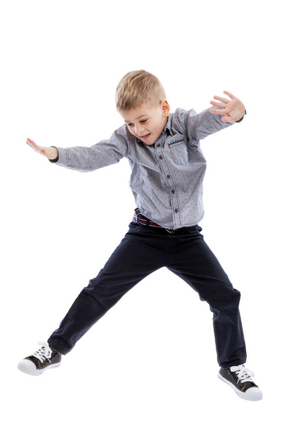 A little boy in jeans and a shirt is jumping. Isolated on a white background. Vertical. - Fotografie, Obrázek