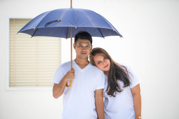 Joven pareja asiática usando una camiseta blanca está de pie fuera de la casa
. - Foto, Imagen