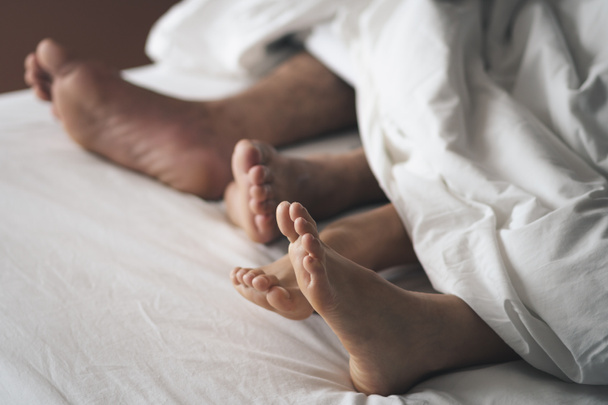 Close-up van de voeten van een echtpaar op het bed. Koppels bedrijven de liefde een - Foto, afbeelding