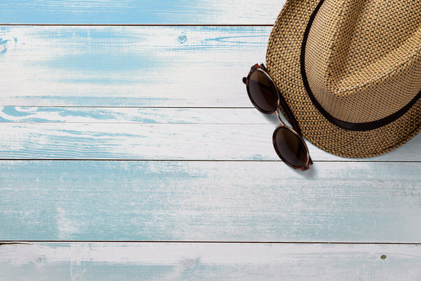 Hat and sunglasses. Top view. Summer concept elements. On turquoise wooden table. - Photo, Image