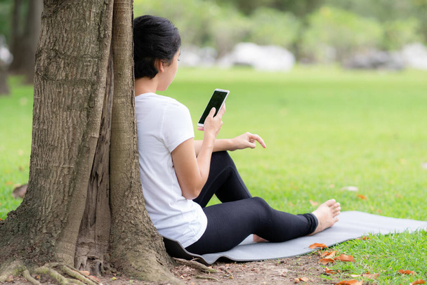 Young woman using smartphone while sitting in a park. - Foto, immagini