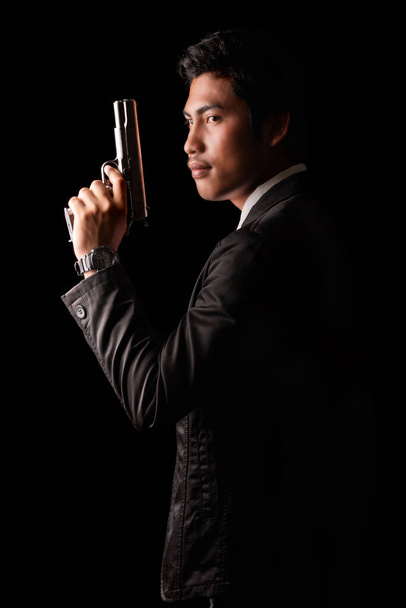 Low key portrait of young man with gun - Photo, Image