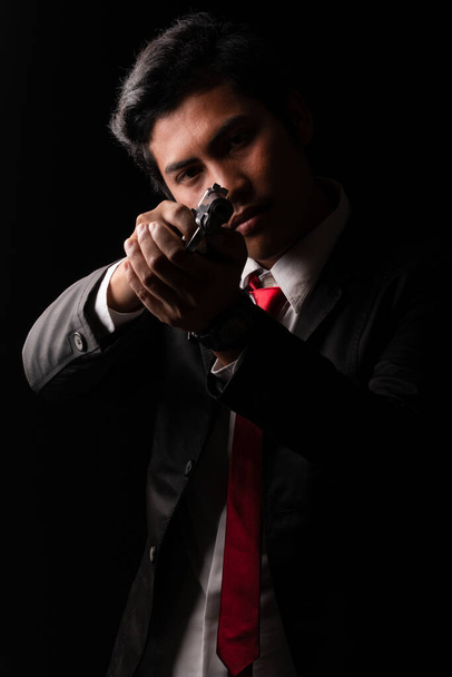 Low key portrait of young man aiming gun. - Photo, Image