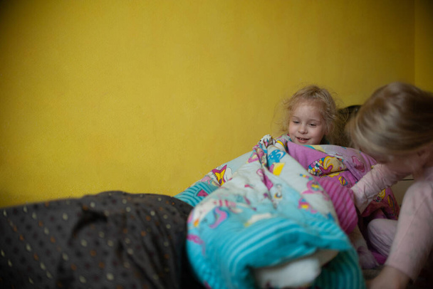  İki kız kardeş yatakta bir daktiloyla oynuyorlar. - Fotoğraf, Görsel