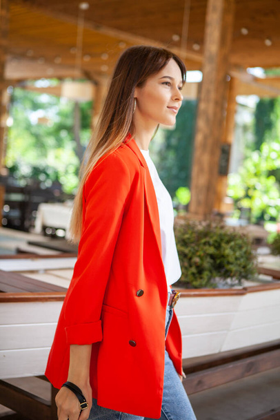 meisje in jeans en een rode jas staan in een restaurant - Foto, afbeelding