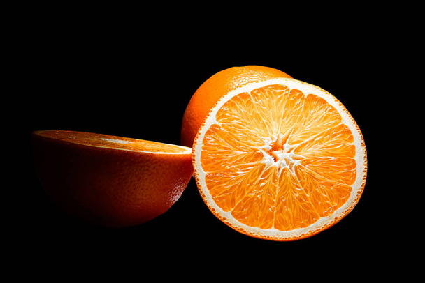 Orange Fruit in Selective Lighting. Isolated on Black Background. - 写真・画像