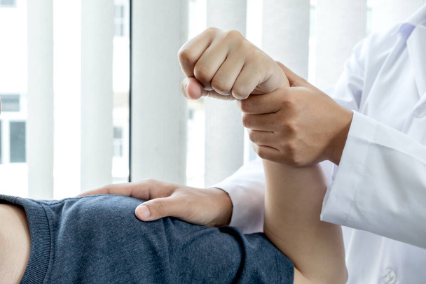 Female physiotherapists provide assistance to male patients with elbow injuries examine patients in rehabilitation centers. Physiotherapy concepts. - Photo, Image