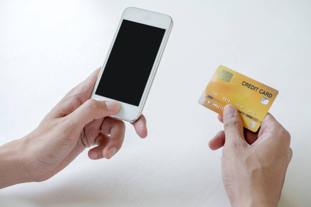 Νέοι άνθρωποι που κατέχουν πιστωτικές κάρτες και smartphones για online αγορές και πληρωμές μέσω Διαδικτύου. - Φωτογραφία, εικόνα