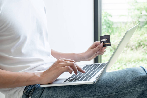 Jóvenes que tienen tarjetas de crédito y usan computadoras portátiles para hacer compras en línea y hacer pagos por Internet
. - Foto, Imagen