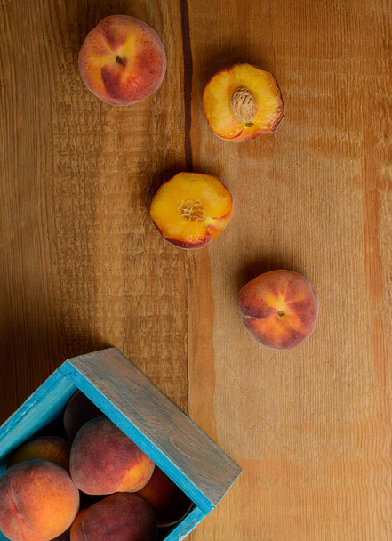 Свежие спелые персики в синей коробке на деревянном деревенском фоне. Вид сверху
. - Фото, изображение