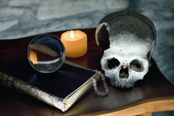 Occulte mystieke rituele relikwieën - menselijke schedel, kaars, kristallen bol, oud boek en spin - Foto, afbeelding