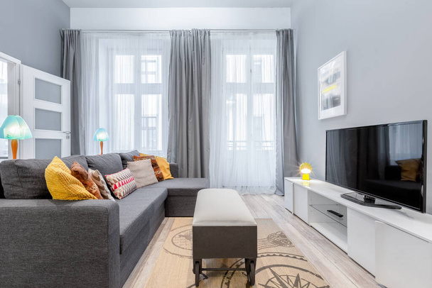 Living room with big windows, grey corner sofa and stylish coffee table on wheels - Zdjęcie, obraz