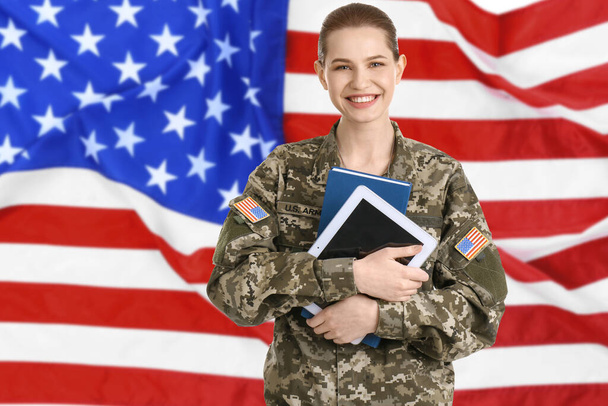 Female soldier with tablet and American flag on background. Military service - 写真・画像