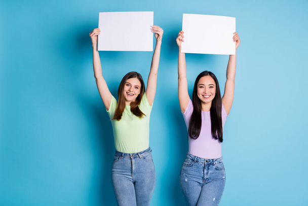 Foto von lustigen zwei Personen Damen Lesben Paar halten Arme steigen weiße Poster unterstützen gleichgeschlechtliche Ehen gute Laune tragen lässig grün violette T-Shirts Jeans isoliert blaue Farbe Hintergrund - Foto, Bild