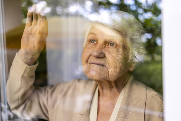 Senior mulher olhando pela janela em casa - Foto, Imagem