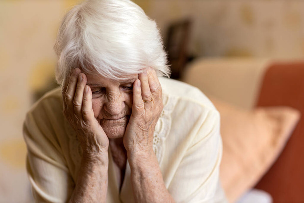 Senior woman holding head in hands in despair  - Fotografie, Obrázek