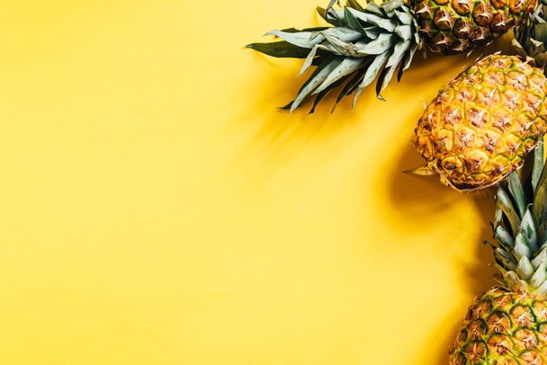 top view of fresh ripe pineapples on yellow background - Fotoğraf, Görsel