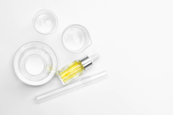 Líquido cosmético amarelo (óleo). Produtos químicos para cuidados de beleza na mesa de laboratório branco. (Vista superior
) - Foto, Imagem
