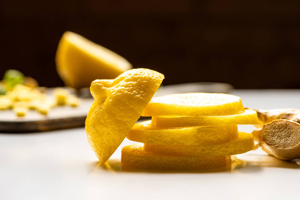 selective focus of sliced lemon and ginger root on white and black background - Zdjęcie, obraz