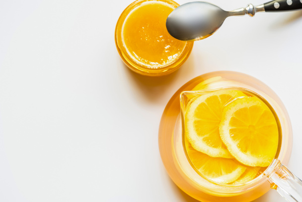 vista superior de chá quente com limão perto de mel com colher no fundo branco
 - Foto, Imagem