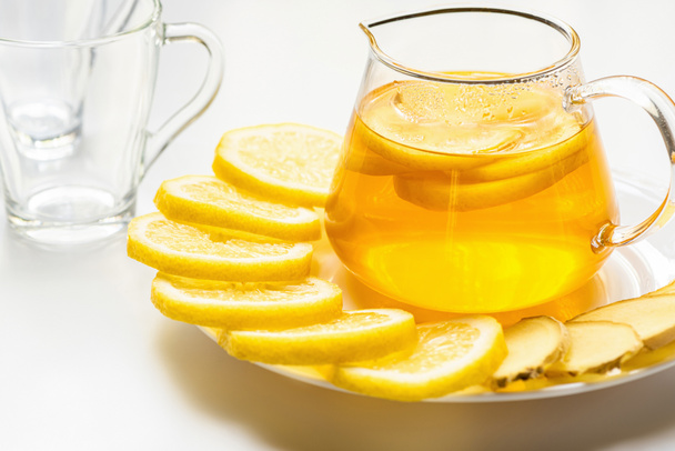 forró tea üveg teáskanna citrom szeletek és gyömbér fehér alapon - Fotó, kép
