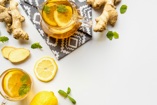 top view of hot tea on napkin near ginger root, lemon and mint on white background - Φωτογραφία, εικόνα