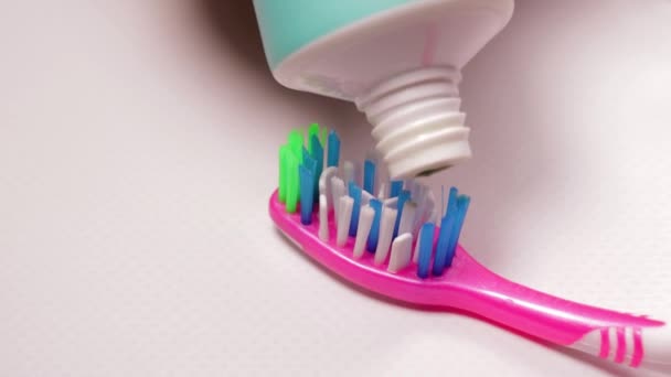 Appliquer un dentifrice vert naturel sur une brosse à dents rose
. - Séquence, vidéo