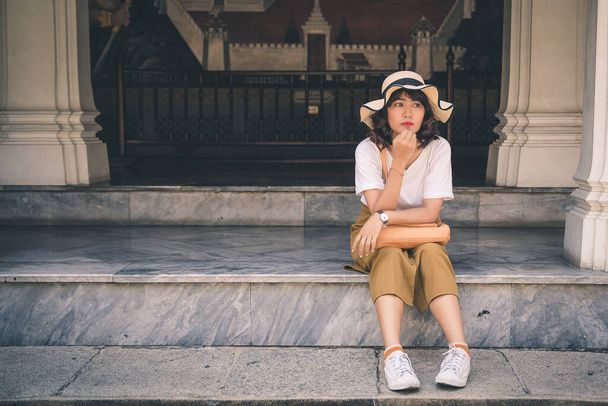 Retrato de una mujer asiática con un sombrero viajando en el templo Phra Kaew en Bangkok, Tailandia
. - Foto, imagen