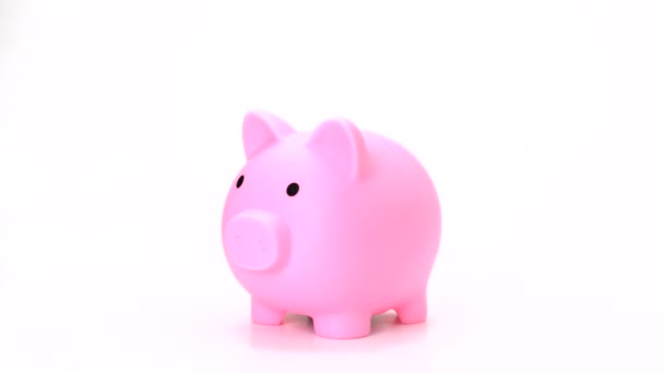 Besparen geld op roze spaarvarken bank isoleren. hand zetten munt in varken pop bank op witte achtergrond- 4k, 1080, fhd, full hd - Video