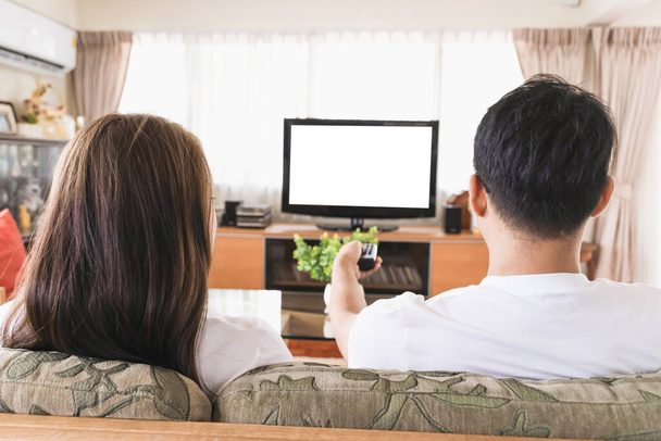 Ασιατικά ζευγάρια βλέπουν τηλεόραση στον καναπέ του σπιτιού.. - Φωτογραφία, εικόνα