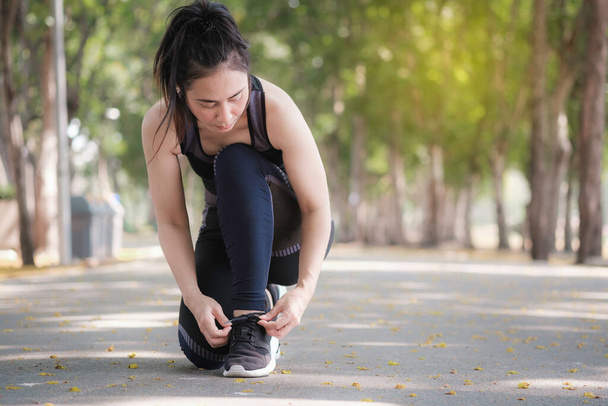 Mujer asiática está usando sujetador deportivo negro y ella es zapato de cordones para prepararse para correr en el parque público. Concepto de salud urbana
. - Foto, Imagen