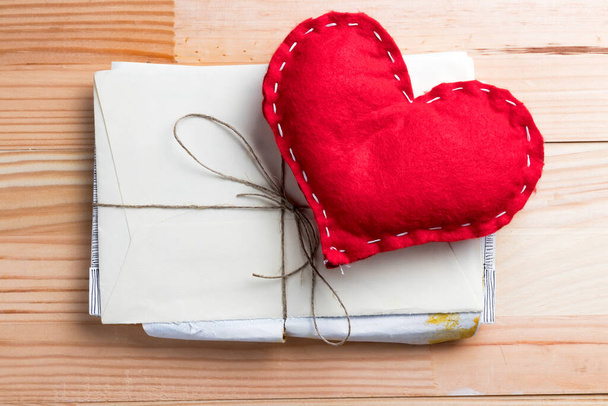 Punainen kotitekoinen sydän joukolla rakkauskirjeitä ystävänpäivänä. Luonnollinen puinen pöytä. - Valokuva, kuva