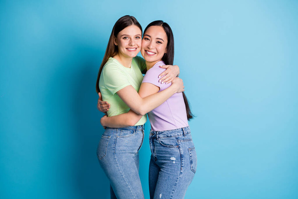 Profile photo of cheerful lesbians couple overjoyed hugging good mood young students best friends fellows buddies wear casual green purple t-shirts jeans isolated blue color background - Φωτογραφία, εικόνα
