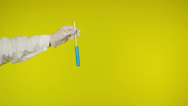 Ręka w rękawicy ochronnej pokazuje szklaną rurkę z jasnoniebieską substancją - Materiał filmowy, wideo