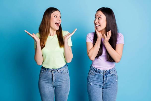 Photo of funny crazy two people ladies lesbians couple overjoyed achievement not believe eyes unexpected good news wear casual t-shirts jeans isolated blue color background - Fotoğraf, Görsel