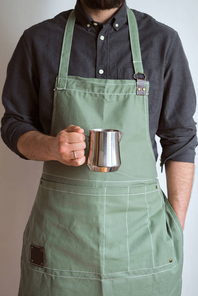 Man hold metal milk pitcher in his hands. Barista milk pitcher closeup. Metal milk jug. Milk frother. Drinks in a cafe. Hot beverage. Equipment for making coffee. Professional coffee service - Zdjęcie, obraz