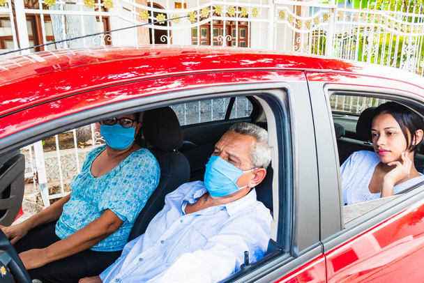 Older man with his family wears a medical mask in the car. Protection against viruse - Photo, Image