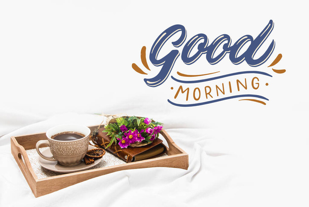 Fresh morning coffee on a board on a bed sheet with the text - Photo, Image