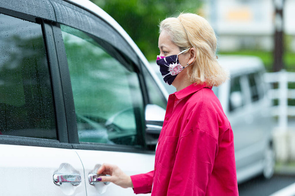 Side view profiili muotokuva sekarotuinen nainen yllään DIY kotitekoinen kangas kasvonaamio suojaa Coronavirus (COVID19) ja muut tartuntataudit. Auton vieressä sateisena päivänä. - Valokuva, kuva